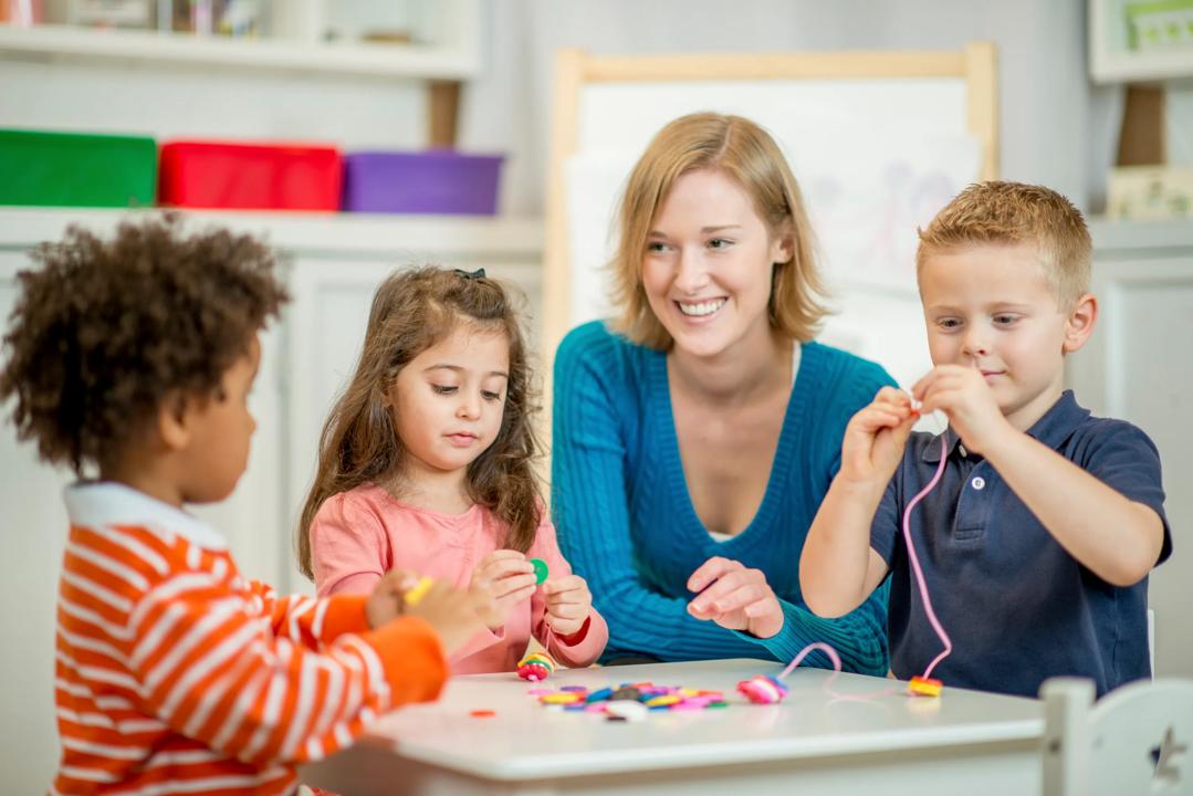 Barn og lærer sitter rundt bord