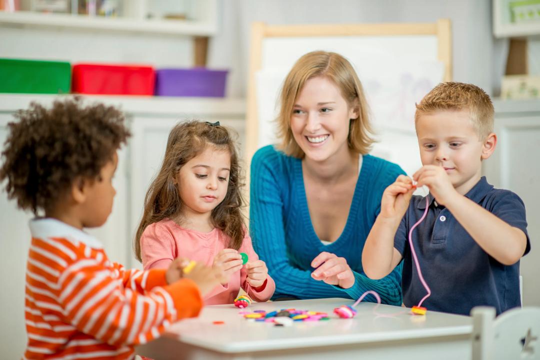 Barn og lærer sitter rundt bord