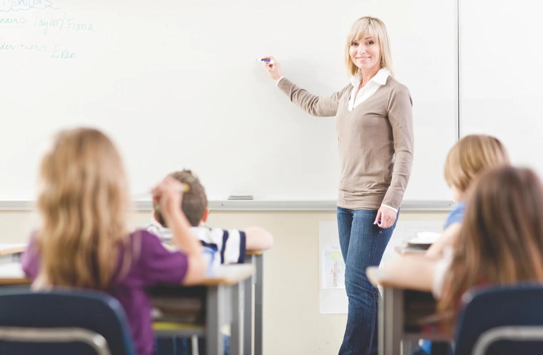 Bilde av en lærer foran skolebarn.