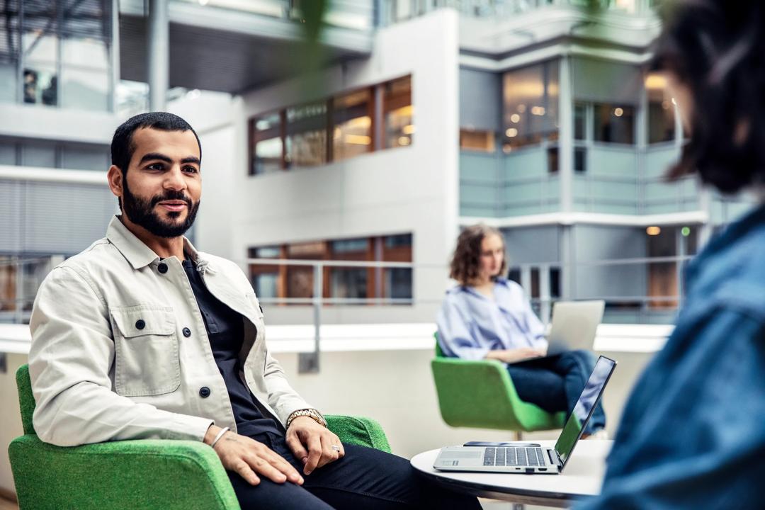 A male at BI sitting and talking to another student