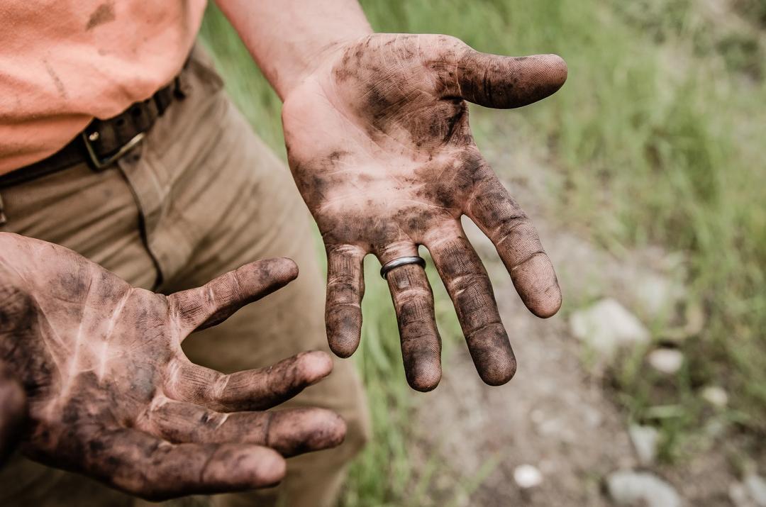 Man with hands covered in mud.
