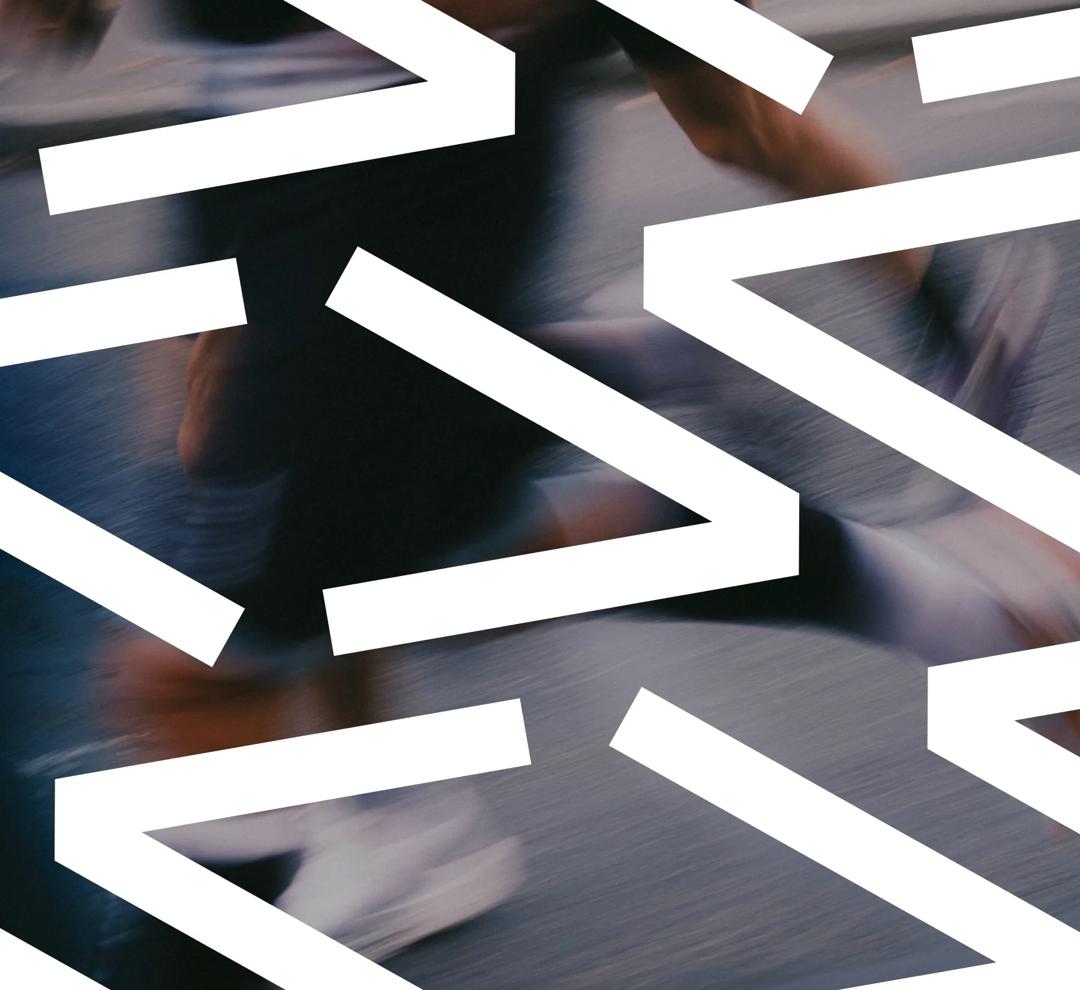 A blurry image of a person running. In the front the letter "V" in white is several places on the image.