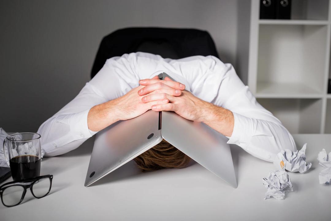 Stresset og fortvilet mann med laptopen over hodet