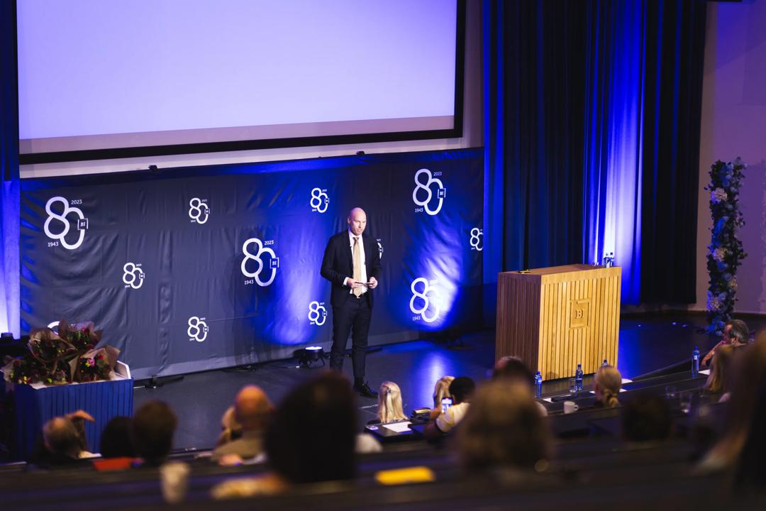 Person som står på scenen og snakker under Alumnidagen 2023