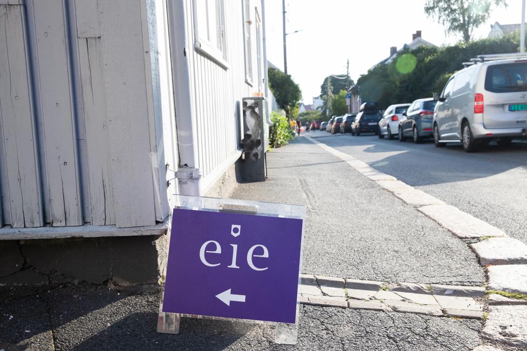 Et visnings-skilt som står en gate foran et hvitt hus