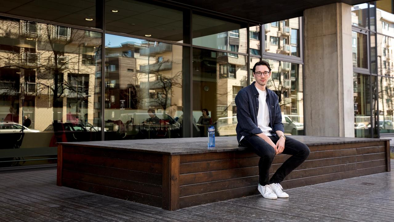 Bilde av en mann med briller foran campus