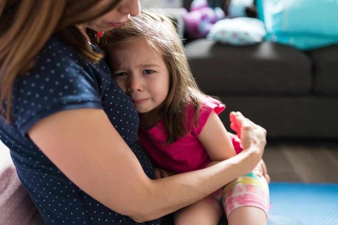 Gråtende jente i fanget på sin mamma